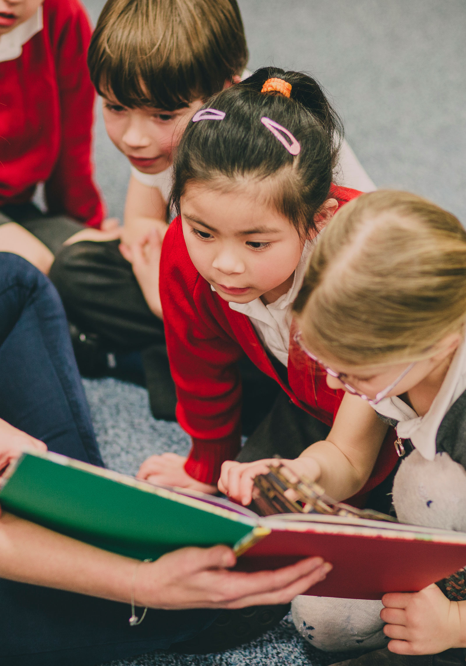 A girl reading a book sitting on the floor at the library.